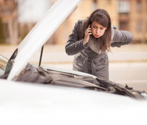 woman looking under hood of car waiting for roadside assistance