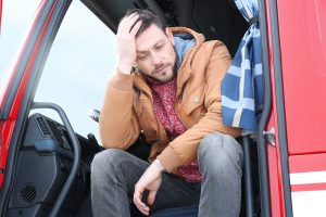 Sad or tired driver in cabin of big modern truck