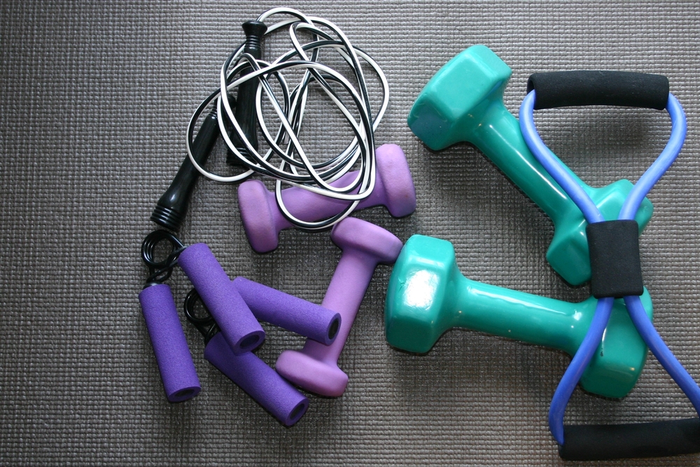 hand weights weights and jump rope on a workout mat